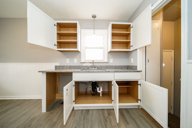 kitchen with white cabinetry, a sink, light wood-style flooring, and open shelves