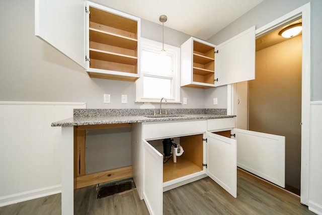 kitchen featuring wood finished floors, a sink, white cabinets, open shelves, and pendant lighting