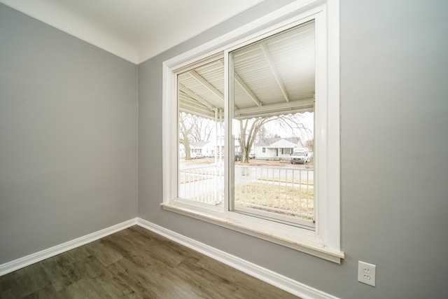 spare room featuring dark wood-style floors and baseboards