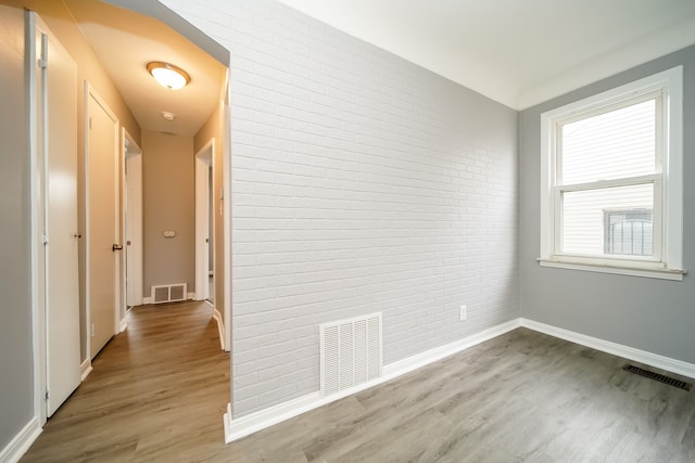 hall featuring brick wall, visible vents, and wood finished floors