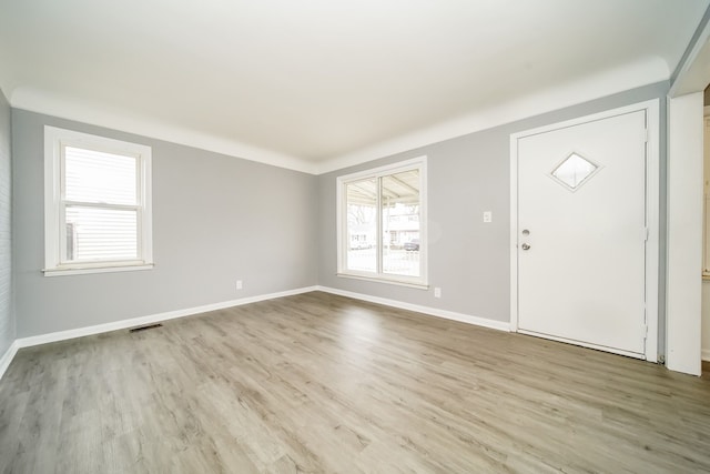 foyer with baseboards, visible vents, and wood finished floors