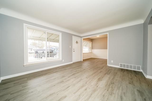 spare room with baseboards, visible vents, and wood finished floors