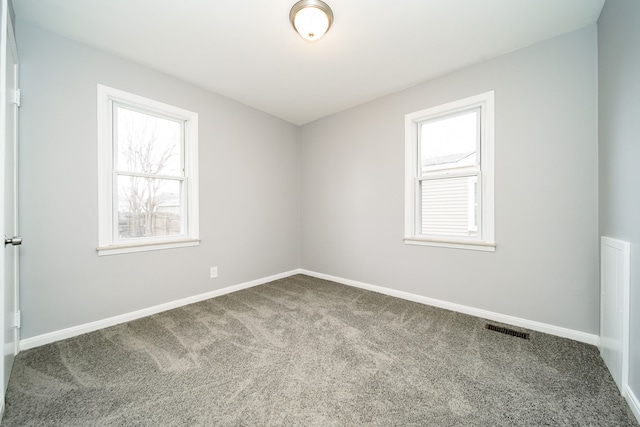 empty room featuring carpet floors, visible vents, and baseboards