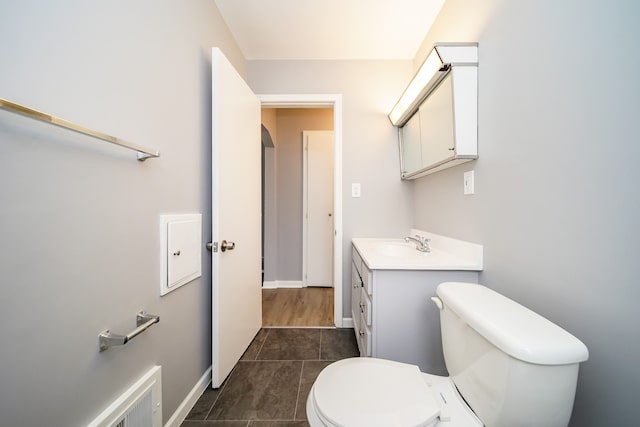 bathroom with toilet, tile patterned flooring, baseboards, and vanity