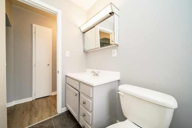 bathroom with toilet, baseboards, and vanity