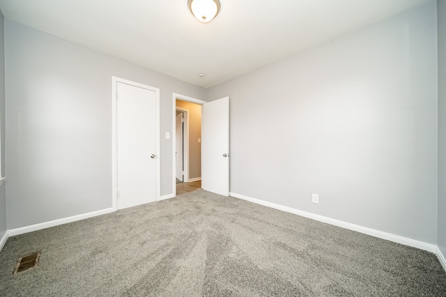 empty room with baseboards, visible vents, and carpet flooring