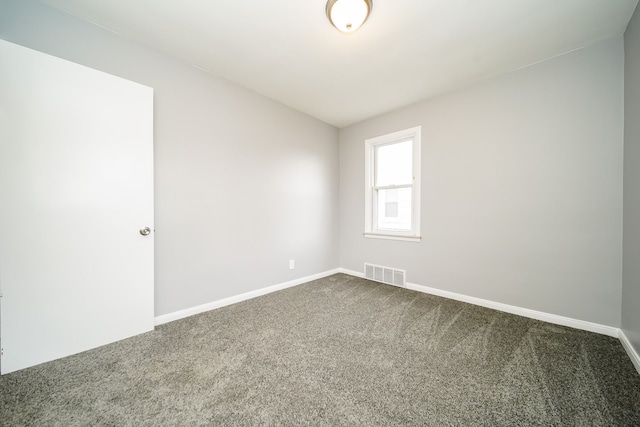 empty room featuring baseboards, visible vents, and dark carpet