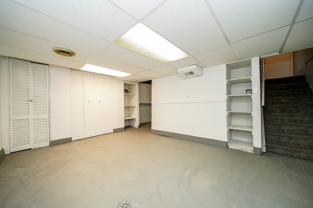 finished basement with a paneled ceiling and stairs