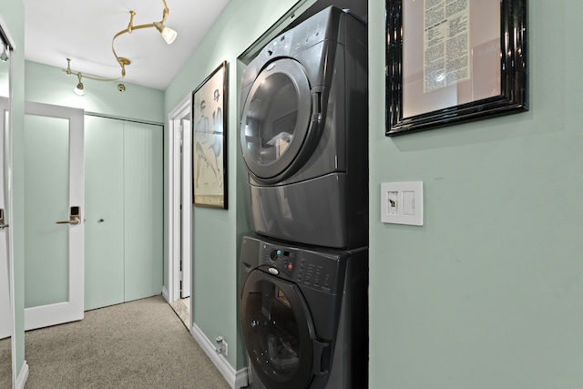 washroom featuring carpet floors, stacked washer / dryer, laundry area, and baseboards