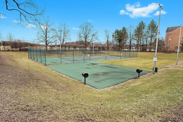 view of sport court featuring a tennis court, fence, and a yard