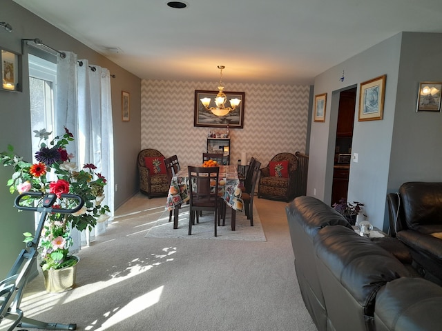 dining room with light carpet, an accent wall, visible vents, wallpapered walls, and an inviting chandelier