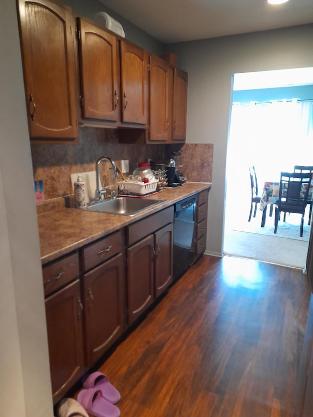 kitchen with decorative backsplash, dishwasher, dark wood-type flooring, light countertops, and a sink