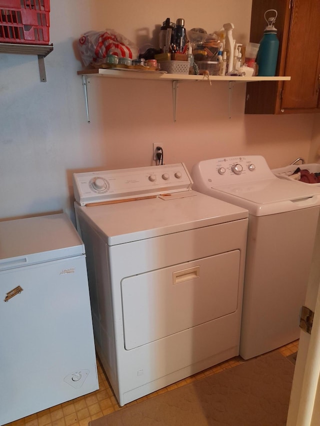 laundry area with cabinet space, washing machine and dryer, and light floors