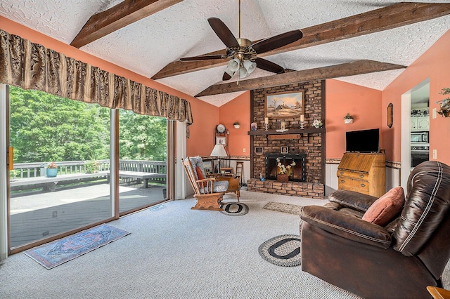 carpeted living room with lofted ceiling with beams, a brick fireplace, a ceiling fan, and a textured ceiling