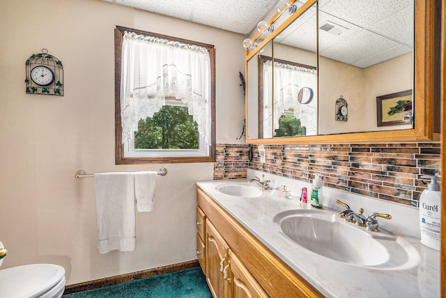 bathroom featuring a wealth of natural light, visible vents, a drop ceiling, and a sink