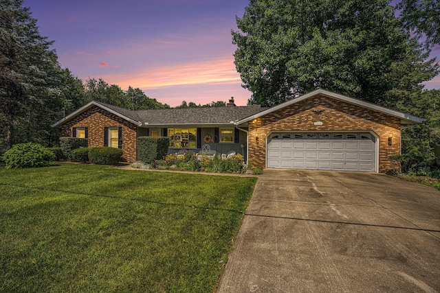 ranch-style home featuring driveway, an attached garage, a lawn, and brick siding