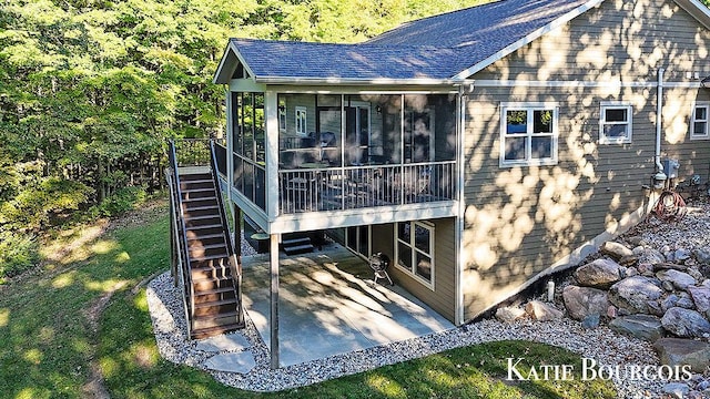 view of side of home with a shingled roof, a lawn, a patio, a sunroom, and stairway