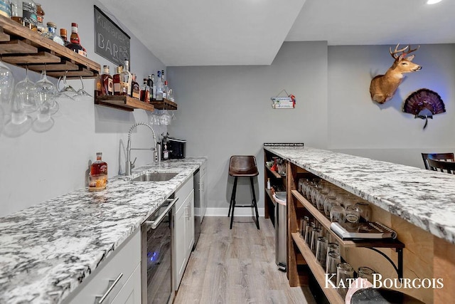 kitchen with open shelves, light wood-style flooring, white cabinetry, a sink, and light stone countertops