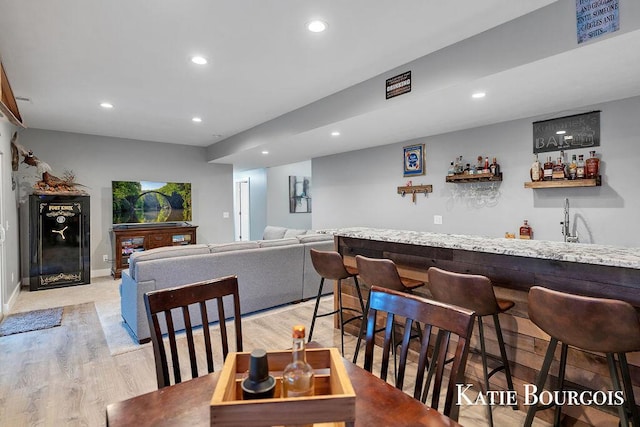 interior space featuring wet bar, baseboards, light wood finished floors, and recessed lighting