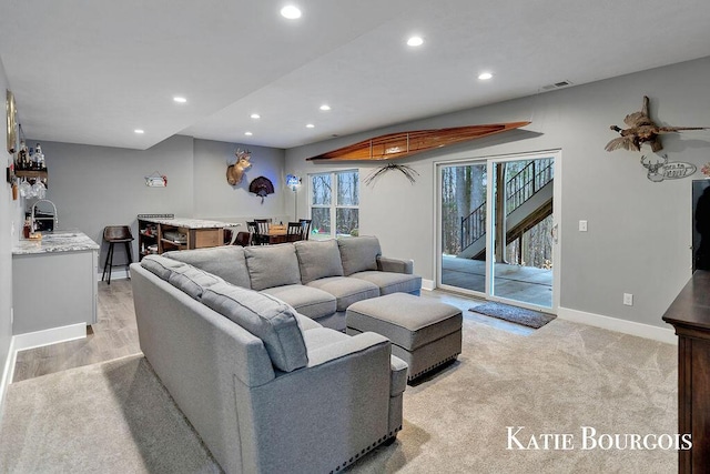 living room featuring recessed lighting, visible vents, light carpet, baseboards, and stairs