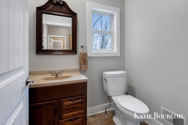 half bathroom with baseboards, visible vents, vanity, and toilet