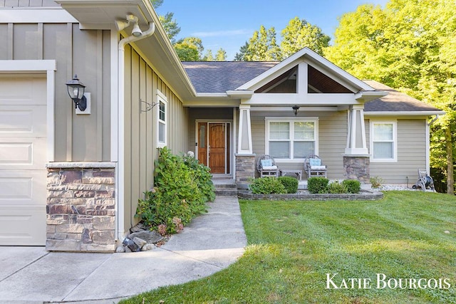 entrance to property with board and batten siding, stone siding, a lawn, and an attached garage