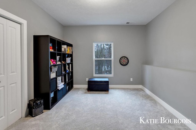 sitting room with carpet flooring, visible vents, baseboards, and a textured ceiling