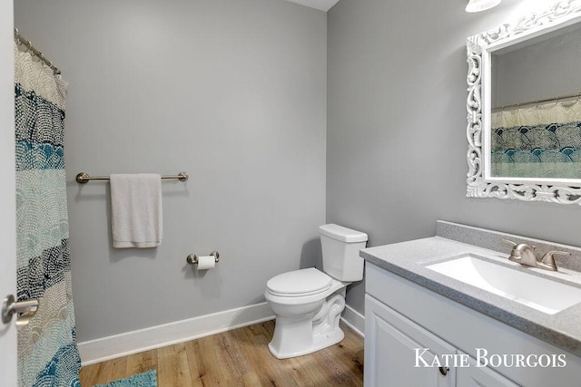 bathroom featuring toilet, wood finished floors, vanity, and baseboards