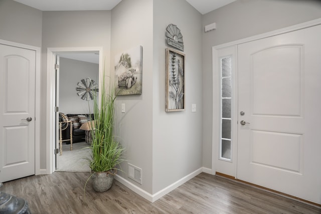 foyer entrance featuring wood finished floors, visible vents, and baseboards