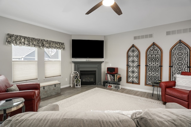 living area featuring visible vents, wood finished floors, and a glass covered fireplace