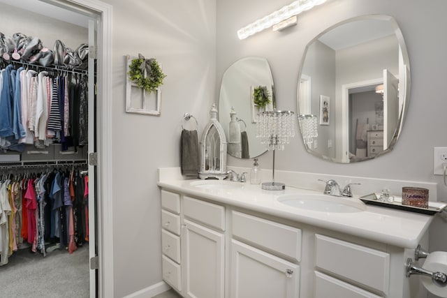 full bathroom with double vanity, a walk in closet, and a sink