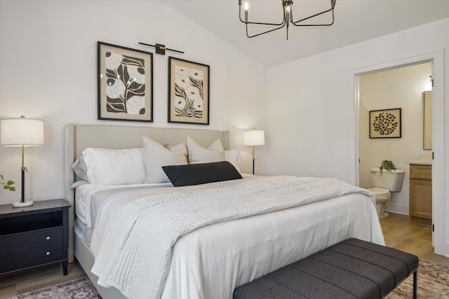 bedroom with a notable chandelier, connected bathroom, vaulted ceiling, and wood finished floors