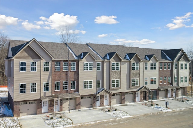 townhome / multi-family property featuring driveway, a garage, and brick siding