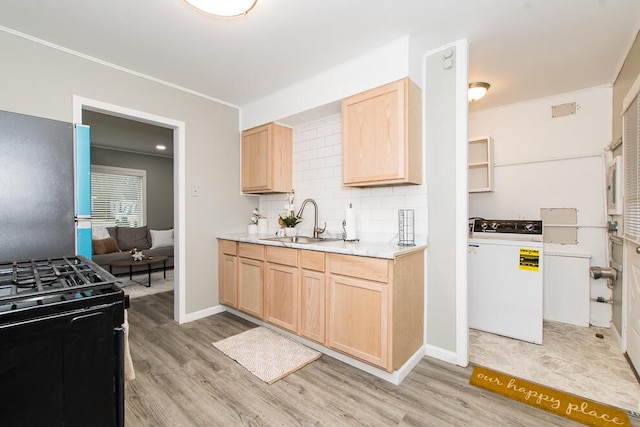 kitchen with washer / dryer, a sink, decorative backsplash, and light brown cabinetry