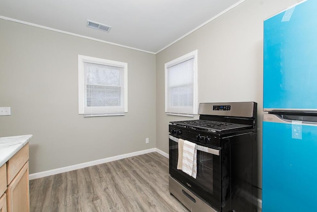 kitchen with stainless steel range with gas cooktop, crown molding, light wood finished floors, visible vents, and freestanding refrigerator