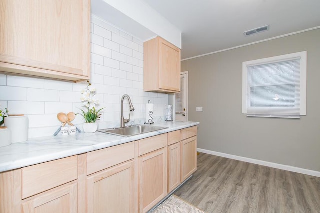 kitchen with crown molding, visible vents, a sink, and light brown cabinetry