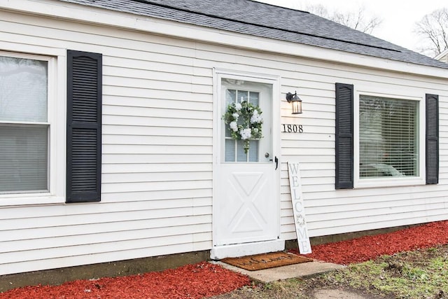 property entrance featuring a shingled roof