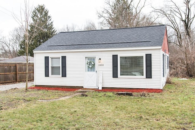 bungalow-style home featuring fence, a front lawn, and roof with shingles