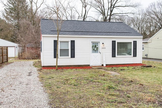 bungalow-style house with roof with shingles, fence, and a front lawn