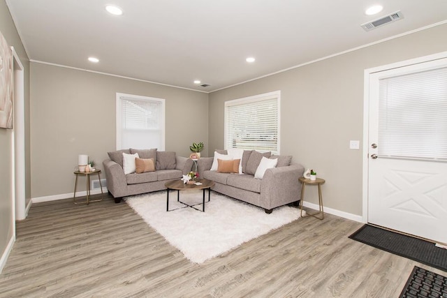 living area with light wood-style flooring, recessed lighting, visible vents, and crown molding