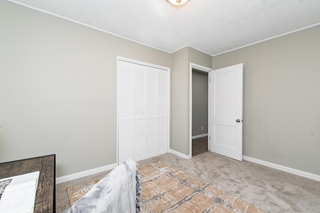 unfurnished bedroom with carpet floors, ornamental molding, a closet, and baseboards