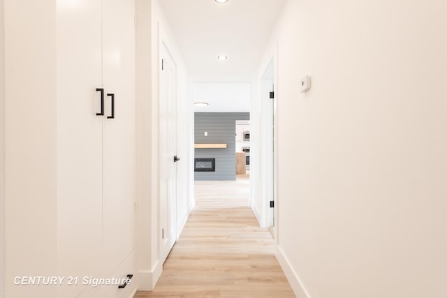 hallway with light wood-style floors, baseboards, and recessed lighting