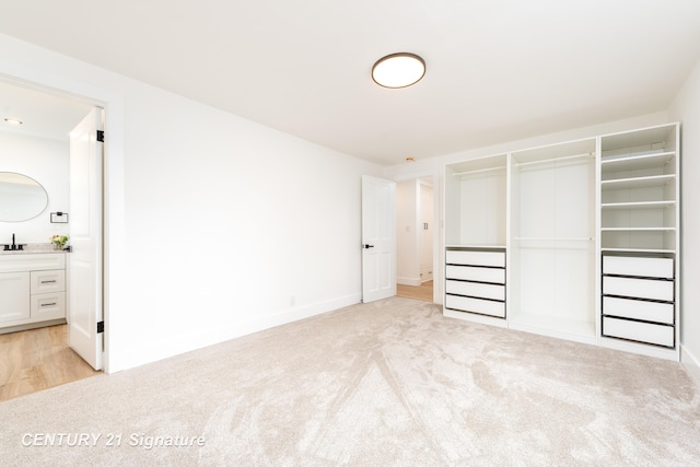 unfurnished bedroom with a closet, ensuite bath, and light colored carpet