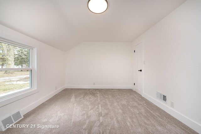 spare room featuring lofted ceiling, baseboards, visible vents, and carpet