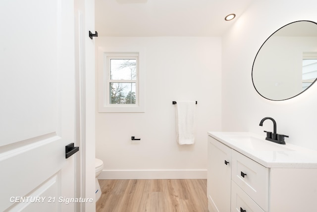 half bath with baseboards, toilet, wood finished floors, vanity, and recessed lighting