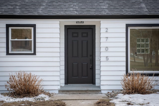 view of exterior entry with a shingled roof