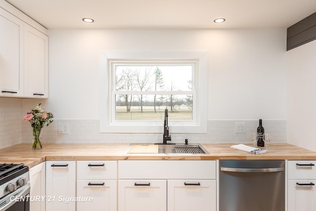 kitchen with butcher block counters, a sink, white cabinetry, appliances with stainless steel finishes, and backsplash