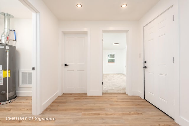 hallway featuring water heater, light wood-type flooring, visible vents, and recessed lighting