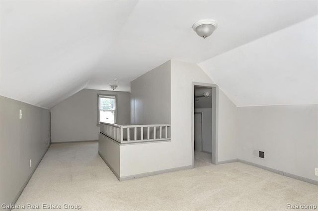 additional living space with carpet, visible vents, baseboards, and vaulted ceiling