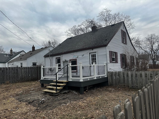 rear view of house with roof with shingles, a chimney, a fenced backyard, and a wooden deck